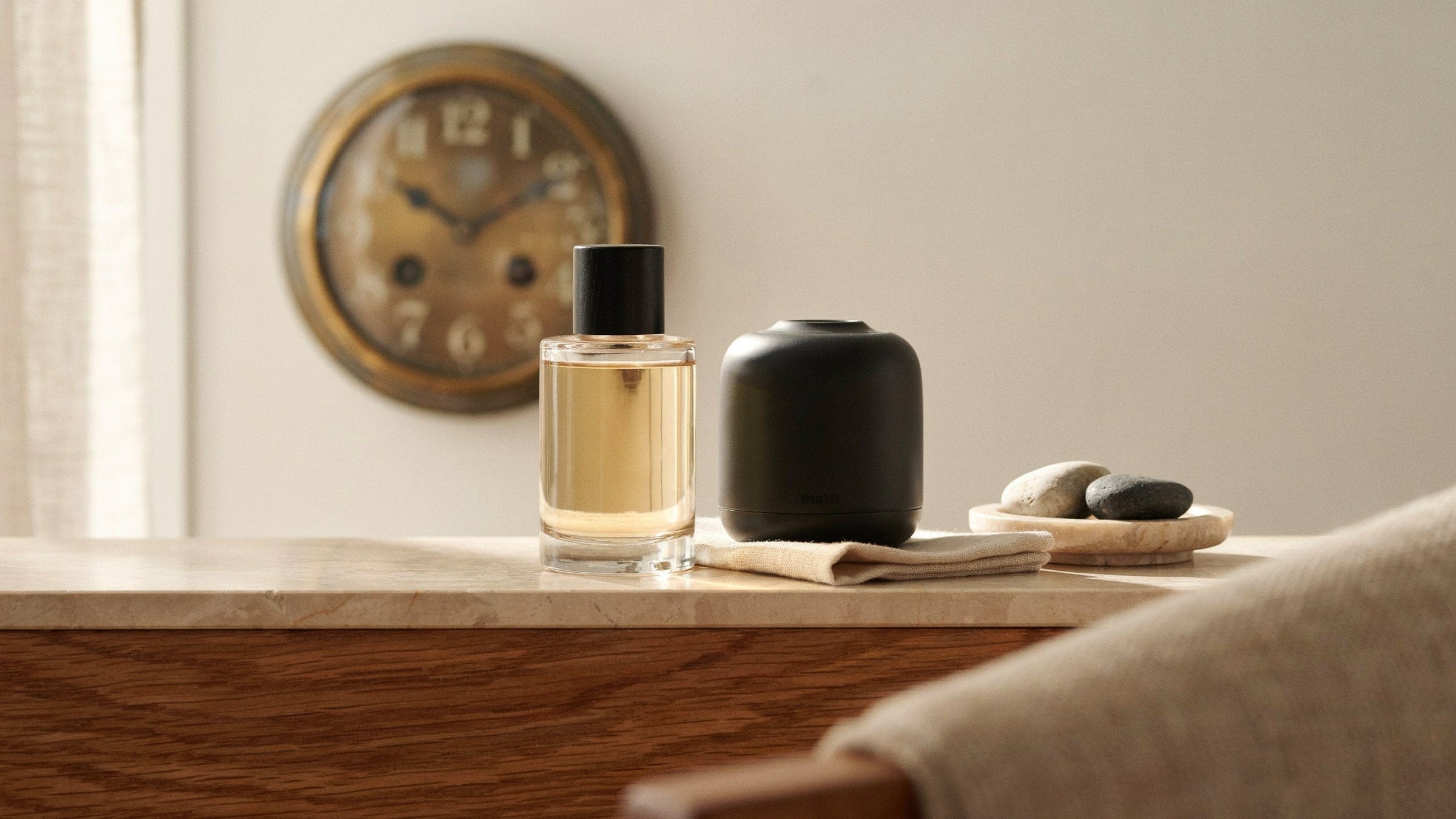 Huile parfumée et diffuseur sans eau à côté d'une horloge légèrement floue dans un salon chaleureux
